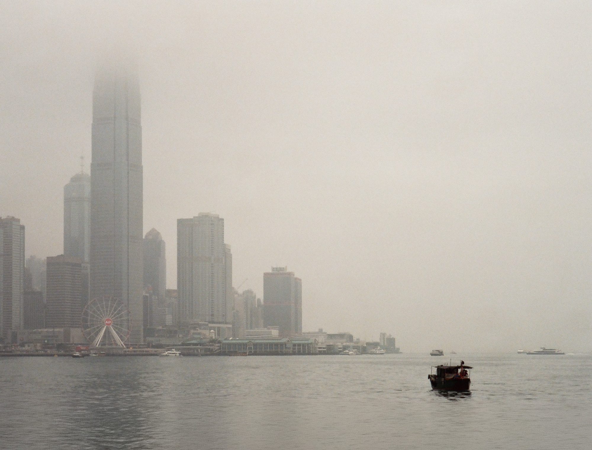 Skyline dissolving into haze, a small boat