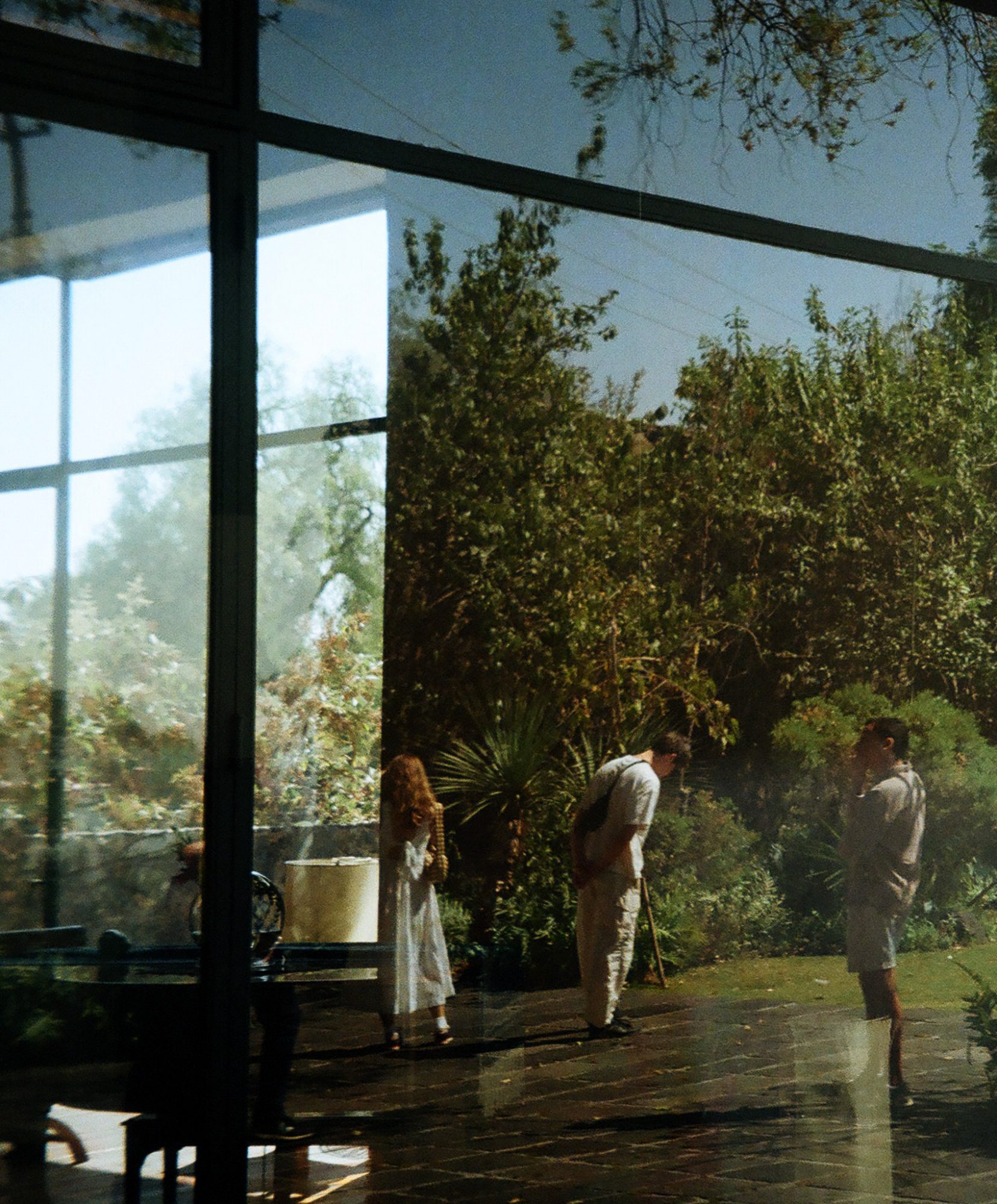 Three figures in a garden, seen through a reflecting window